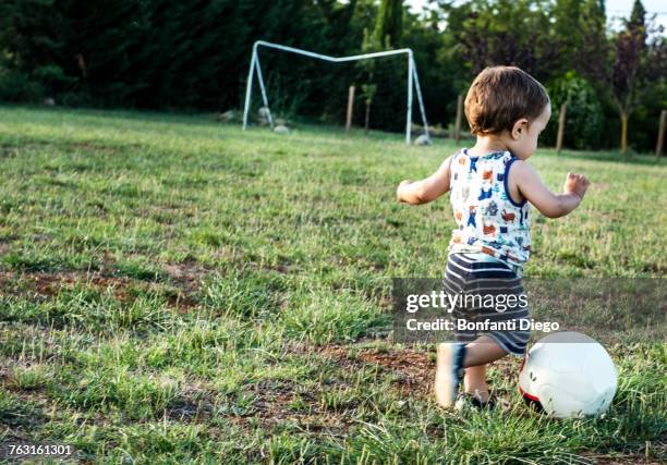 toddler playing football in park - baby football foto e immagini stock