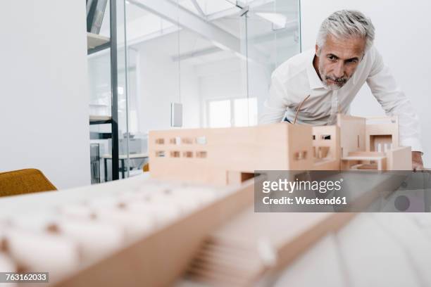 mature businessman examining architectural model in office - architekturmodell stock-fotos und bilder