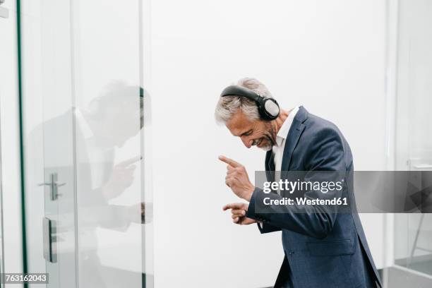 happy mature businessman in office wearing headphones - casual business man stock-fotos und bilder