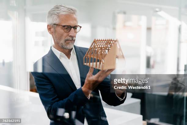 businessman examining architectural model in office - architect stockfoto's en -beelden