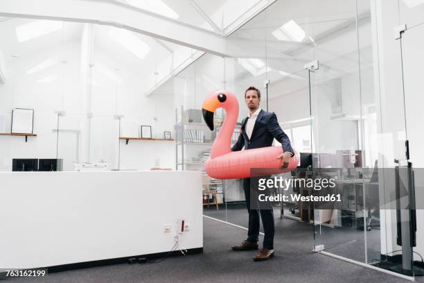 businessman in office with inflatable flamingo - holiday fun stockfoto's en -beelden