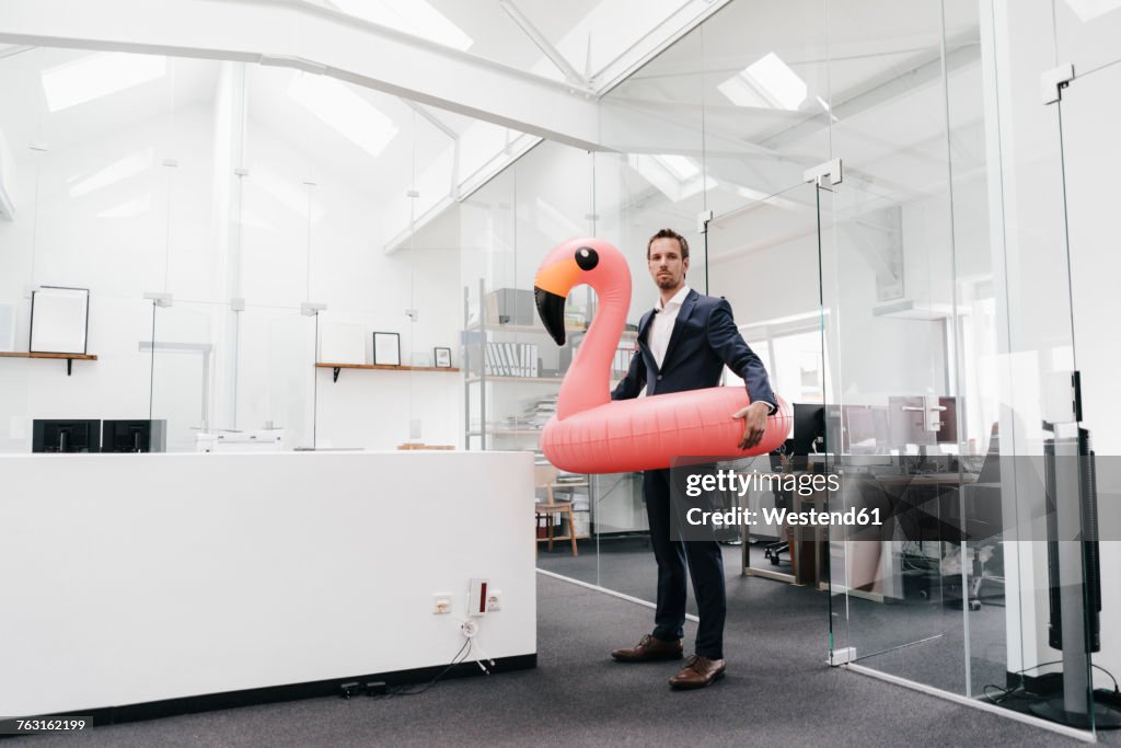 Businessman in office with inflatable flamingo