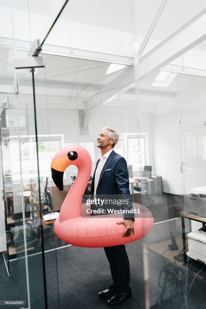 Businessman in office with inflatable flamingo