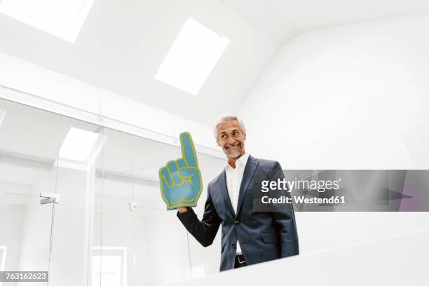 smiling mature businessman holding toy hand in office - hand gag stock-fotos und bilder
