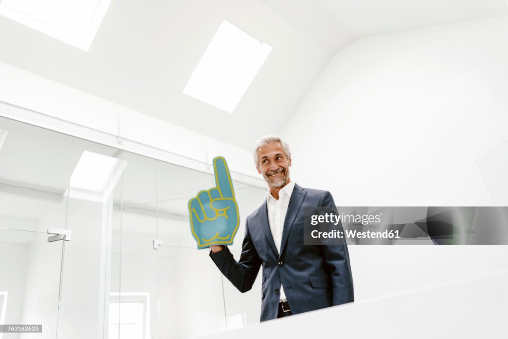 Smiling mature businessman holding toy hand in office