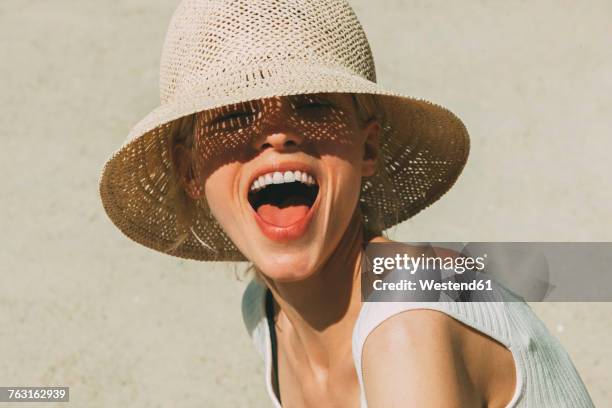 portrait of laughing blond woman wearing summer hat - belleza fotografías e imágenes de stock