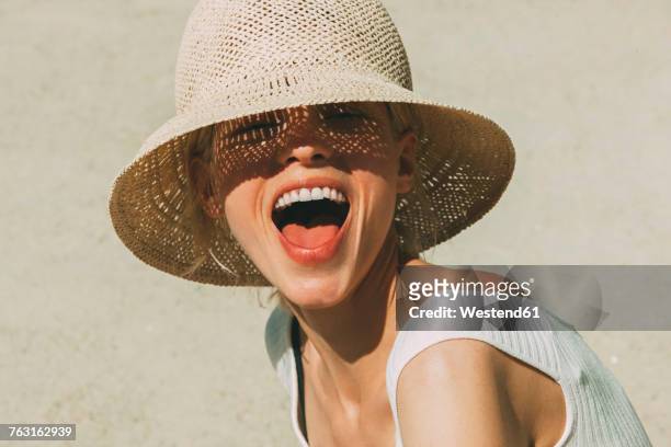 portrait of laughing blond woman wearing summer hat - sun hat stock pictures, royalty-free photos & images