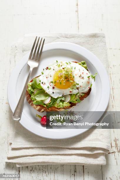 avocado toast with radish, fried egg and micro greens - avocado toast white background stockfoto's en -beelden