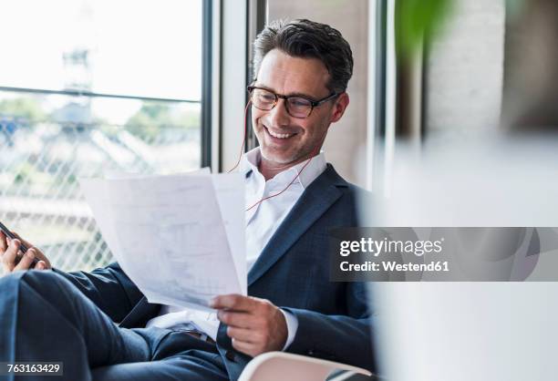 smiling businessman on the phone reading documents - mann anzug gebäude objekt draussen stock-fotos und bilder