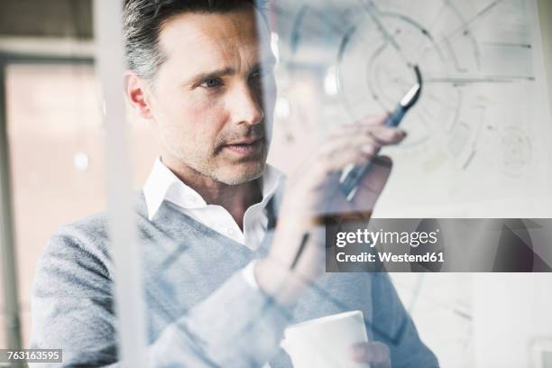 portrait of architect checking construction plan on glass pane in office - taktik stock-fotos und bilder