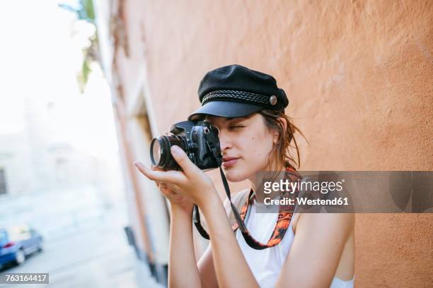 young woman with hat taking a photo with a camera - frauen mit fotoapparat stock-fotos und bilder
