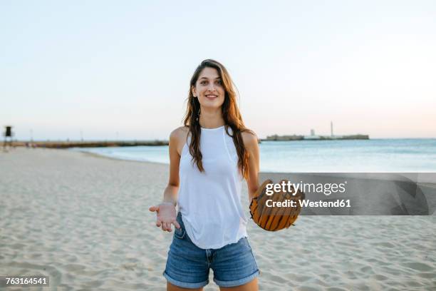 young woman playing with baseball glove on the beach at sunset - passenger train stockfoto's en -beelden