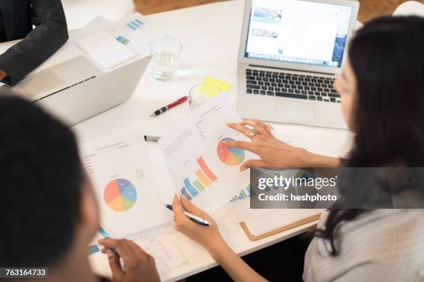 businesswoman discussing pie charts at conference table meeting - heshphoto - fotografias e filmes do acervo