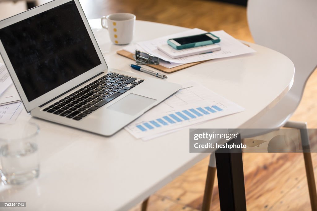 Laptop, bar chart and smartphone on office desk