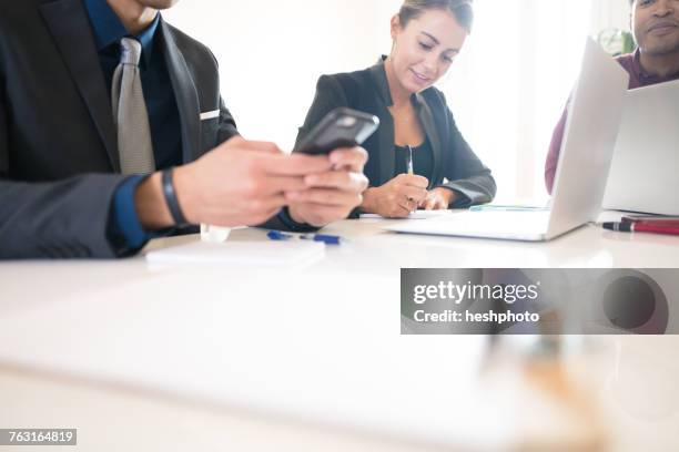 cropped shot of businessman looking at smartphone during meeting - heshphoto stock pictures, royalty-free photos & images