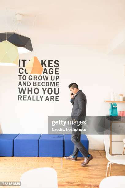 young businessman making smartphone call in creative office - heshphoto stock pictures, royalty-free photos & images