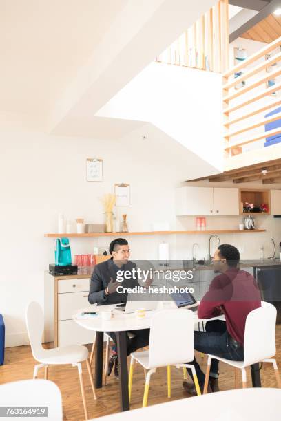 young businessman explaining to colleague at office table - heshphoto stock pictures, royalty-free photos & images