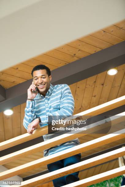 young businessman on balcony making smartphone call - heshphoto stock pictures, royalty-free photos & images