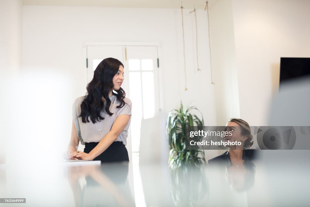 Two businesswomen having discussion while working at office desk