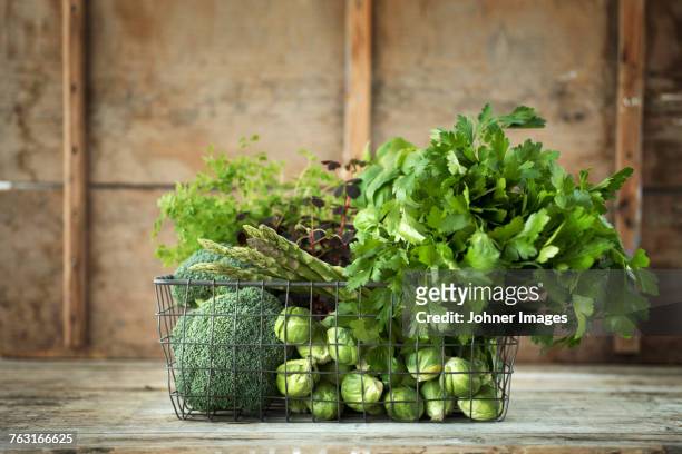 green vegetables and herbs in wire basket - crucifers stock pictures, royalty-free photos & images