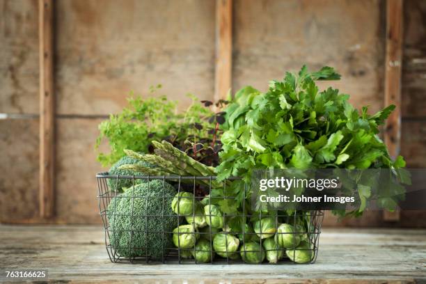 green vegetables and herbs in wire basket - legume de folhas imagens e fotografias de stock