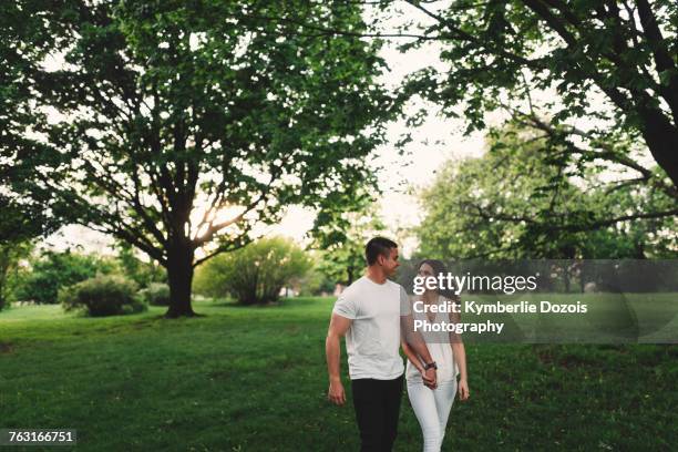 romantic young couple strolling in park holding hands - ottawa park stock pictures, royalty-free photos & images