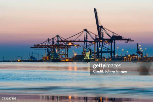 illuminated shipping cranes at dusk - göteborg silhouette bildbanksfoton och bilder