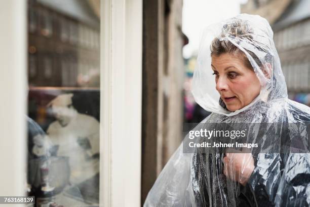 woman wearing rain poncho - storm outside window stock pictures, royalty-free photos & images