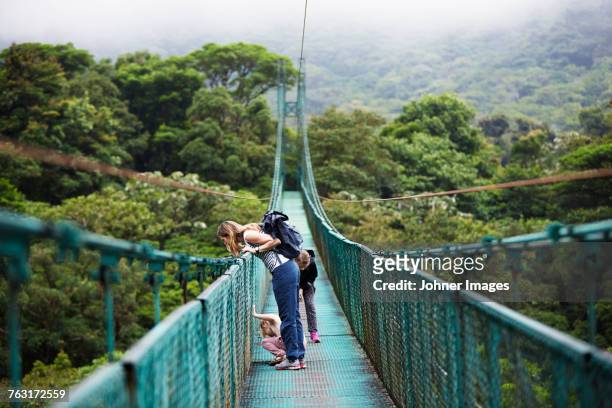 mother with daughters on hanging bridge - costa rica stock pictures, royalty-free photos & images