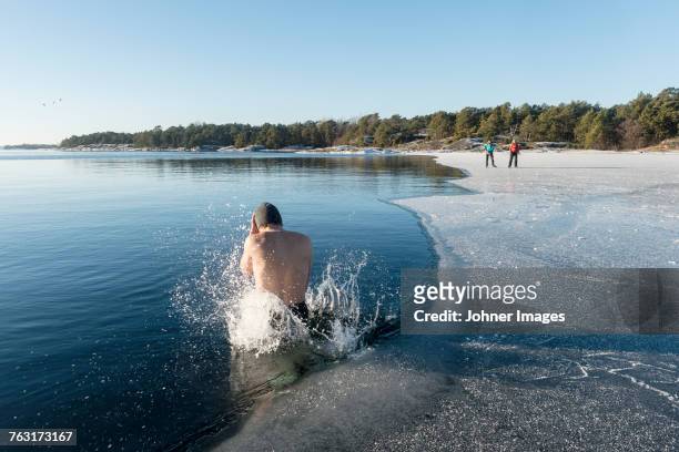 man jumping into freezing cold water - eis baden stock-fotos und bilder