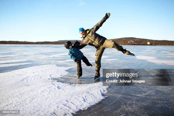 father with son ice-skating on frozen lake - family ice skate stock pictures, royalty-free photos & images