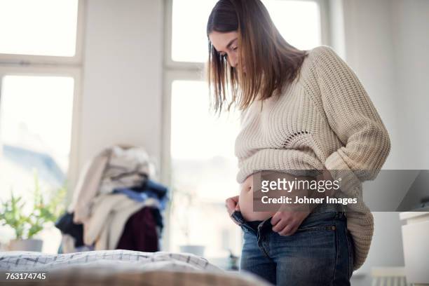 pregnant woman getting dressed - trousers stock-fotos und bilder