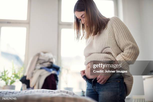 pregnant woman getting dressed - demasiado pequeño fotografías e imágenes de stock