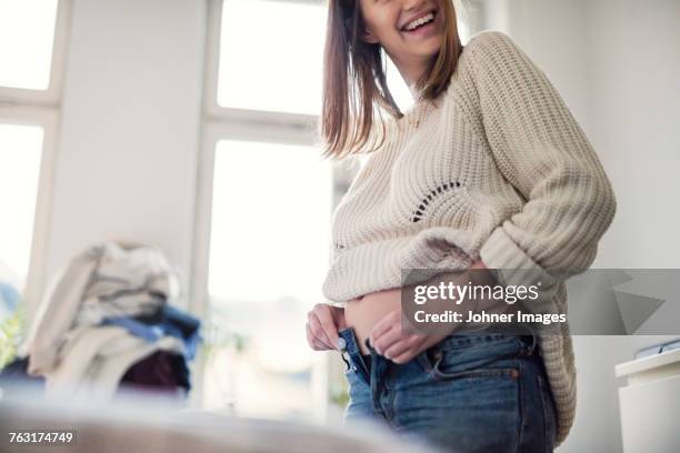 pregnant woman getting dressed - pantalon stockfoto's en -beelden