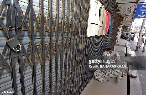 Pakistani street vendor sits in front of shuttered market during a strike in Quetta, 26 August 2007, on the first death anniversary of...