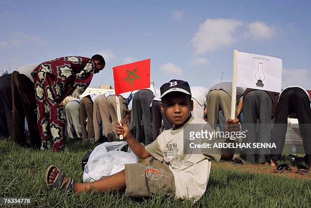 Child holds a Morrocain flag and a opposition Justice and Development Party as party supporters pray 26 August 2007 prior to a electorial campaign...