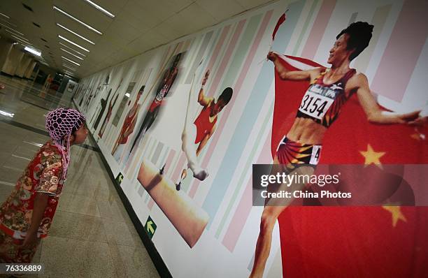 Zhang Huimin views a picture of Chinese Olympic long-running champion Wang Junxia at a subway station during sightseeing on August 26, 2007 in...