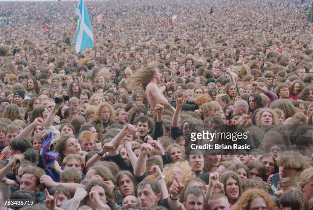 View of a crowd of rock and heavy metal fans and festival goers watching a band perform on stage at the 1994 Monsters of Rock festival at Castle...