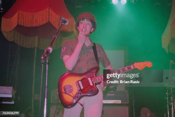 English musician and guitarist Graham Coxon of rock band Blur performs live on stage wearing a military helmet and shirt and playing a Fender Jaguar...