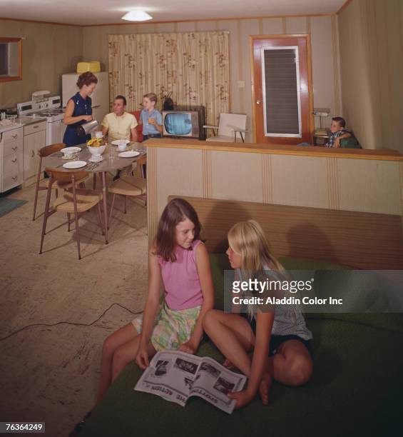 An unidentified family enjoys the amenities offered in an efficiency room at the Monaco Motel, Diamond Point, New York, 1960s. In the foreground, two...