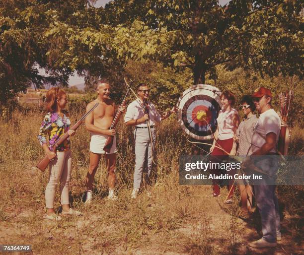 Six people, two with rifles and the rest with bows, smile as they stand near an archery target on the grounds of the Sunnycroft Ranch, Shawangunk,...