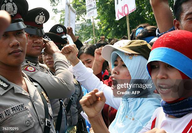 Indonesian migrant workers shout slogans as police guard them during a demonstration at the Soekarno-Hatta International airport in Jakarta, 29...