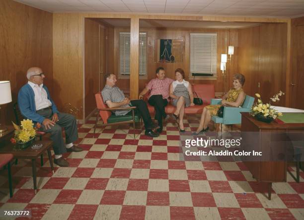 Posed portrait of people as they sit and smile in the lobby of the Mountain Top Inn, West Athens, New York, 1960s. The photographer and his equipment...