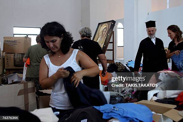 Woman selects clothes offered by the Greek church and civilians inside the Agios Panteleimon church as part of aid to help the victims of fire...