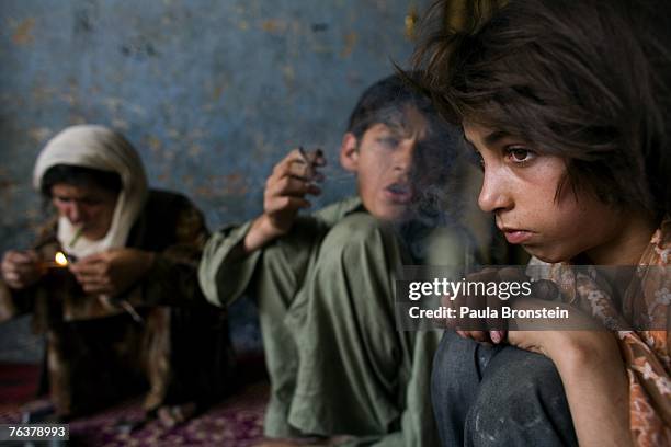 Zaher smokes heroin along side his mother Sabera and sister Gulparai August 27, 2007 in Kabul, Afghanistan. Zaher's mother, Sabera, a widow, has been...