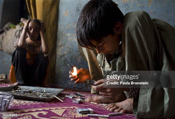 Zaher smokes heroin along side his mother Sabera and sister Gulparai August 27, 2007 in Kabul, Afghanistan. Zaher's mother, Sabera, a widow, has been...
