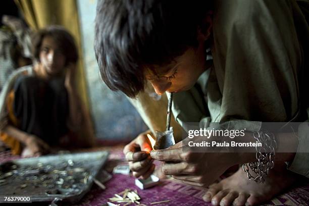 Zaher smokes heroin along side his mother Sabera and sister Gulparai August 27, 2007 in Kabul, Afghanistan. Zaher's mother, Sabera, a widow, has been...