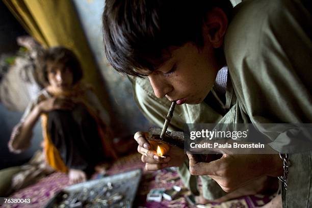 Zaher smokes heroin along side his mother Sabera and sister Gulparai August 27, 2007 in Kabul, Afghanistan. Zaher's mother, Sabera, a widow, has been...