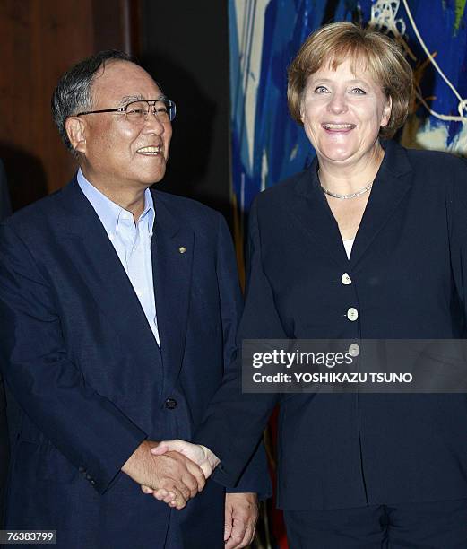 German Chancellor Angela Merkel shakes hands with Japanese business group Keidanren leader Fujio Mitarai chairman of Canon prior to their talks at...