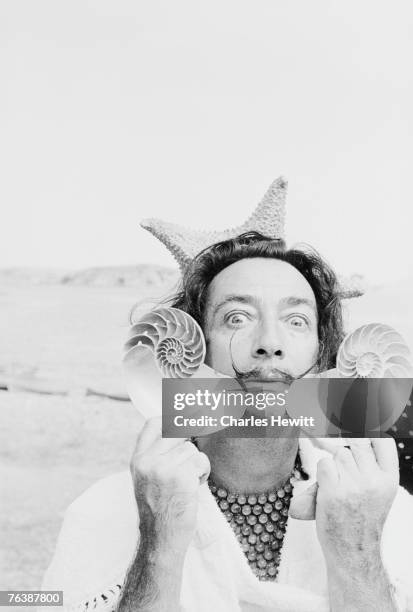 Spanish surrealist artist Salvador Dali holds up two seashells at his home in Cadaques on the Costa Brava, Spain, 8th January 1955. Original...
